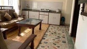 A compact living space with a sofa, a coffee table, a kitchen area with cabinets and appliances, and a patterned floor. - Centrally located at west Thamel quite Location 5 stories Apartment  (Kathmandu)