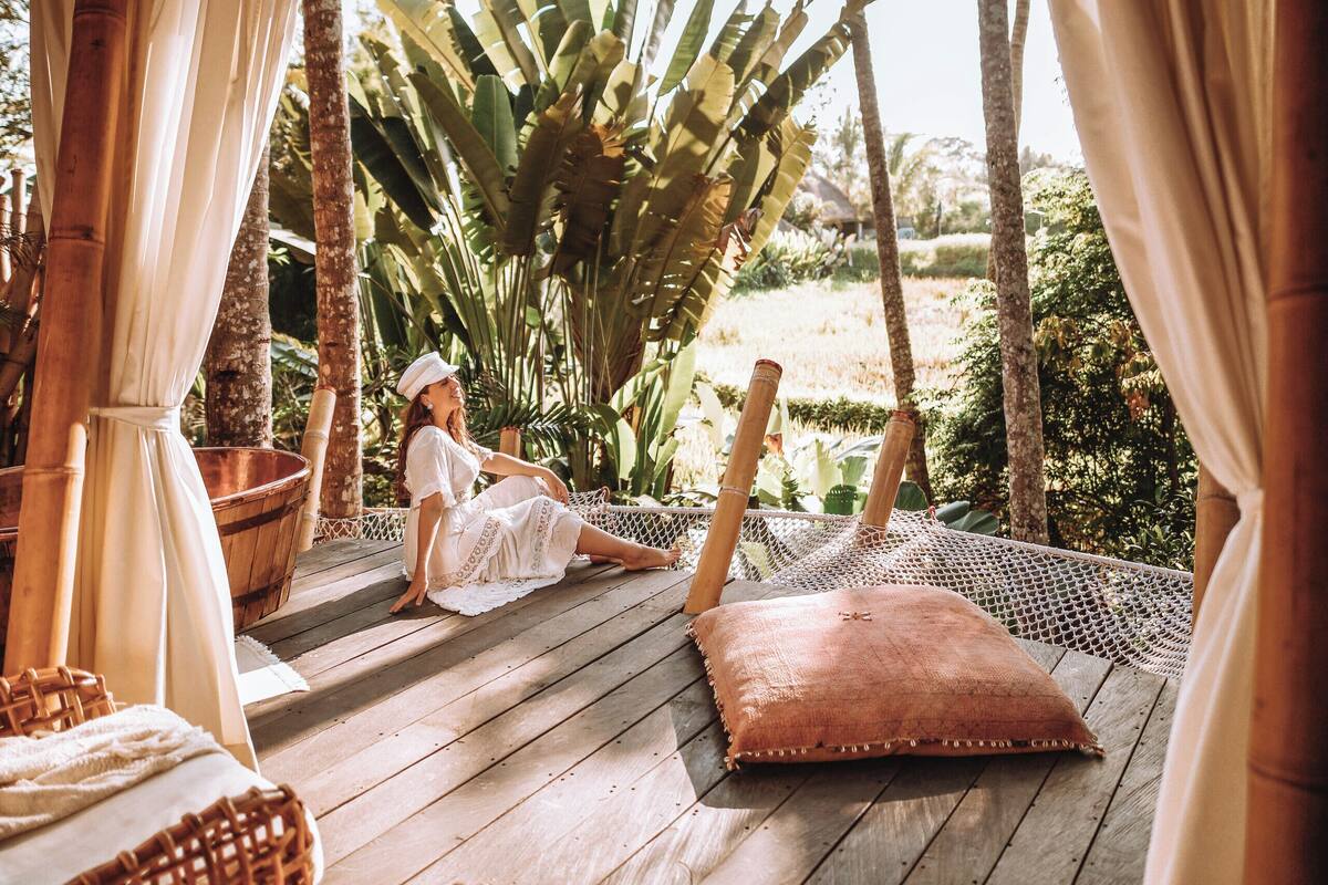 A wooden deck with wicker furniture and a person sitting on the floor.