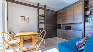 A modern living room with a wooden dining table and chairs, a blue sofa, and built-in wooden shelving with books. - A due passi da Camogli (Recco)