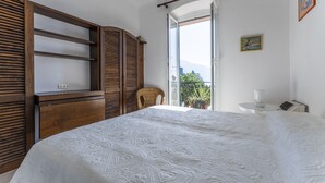 A bedroom with a large bed, wooden wardrobe, and a balcony with a view. - A due passi da Camogli (Recco)