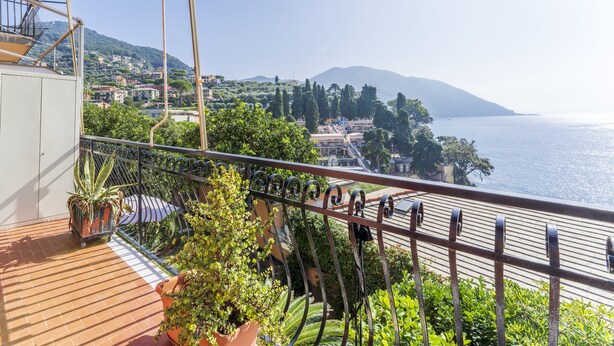 A balcony with a view of the sea and hills, potted plants, and a metal railing. - A due passi da Camogli (Recco)