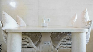 Una mesa blanca con dos sillas, cada una con un cojín blanco.