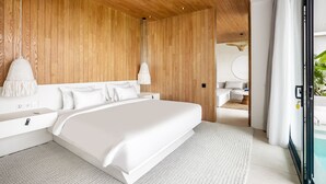 Un dormitorio moderno con una cama grande, paneles de madera, una mesita de noche blanca y vistas a un baño y zona exterior.