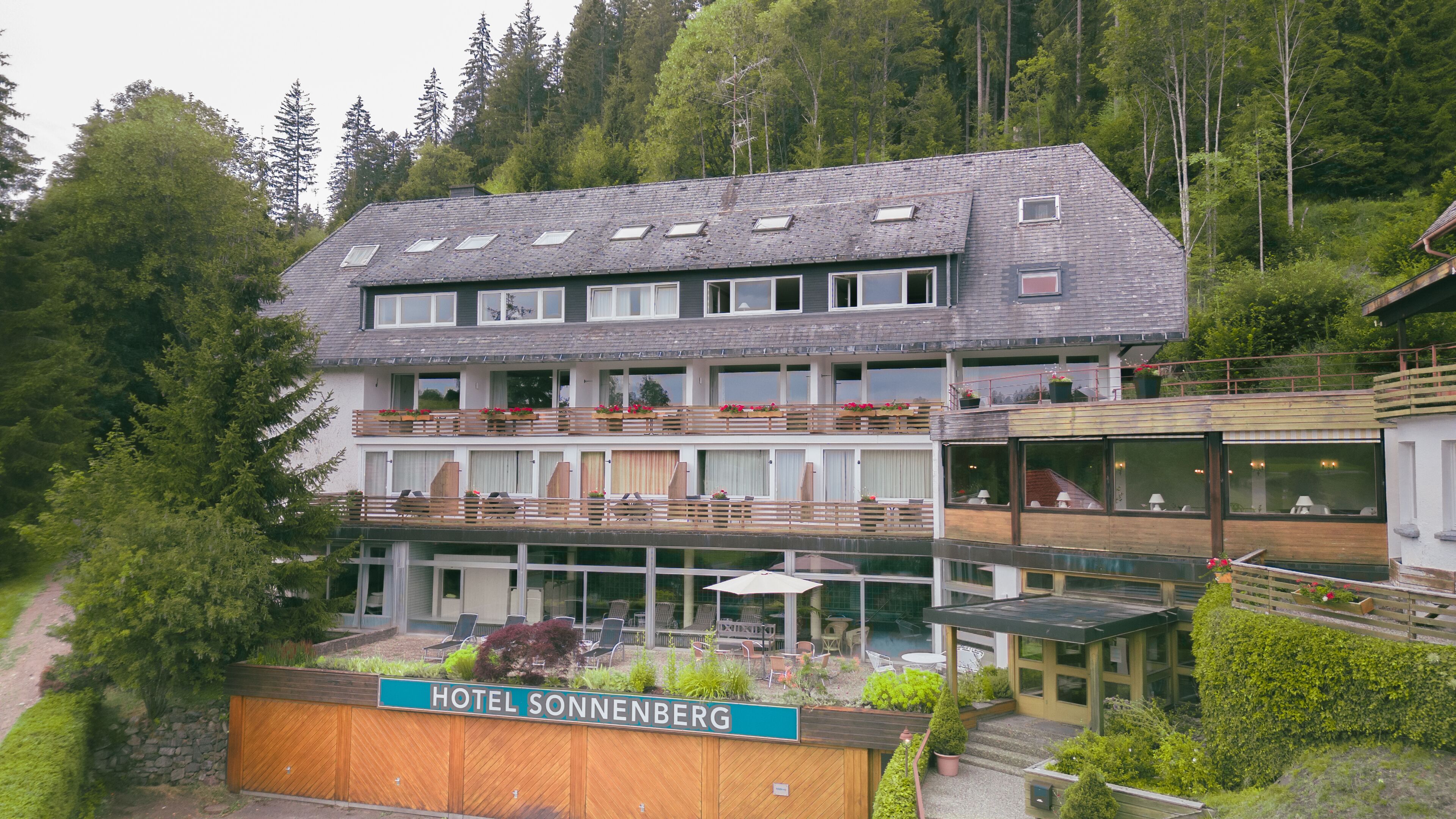 A multi-story hotel with balconies, outdoor seating, and a sign reading "HOTEL SONNENBERG".