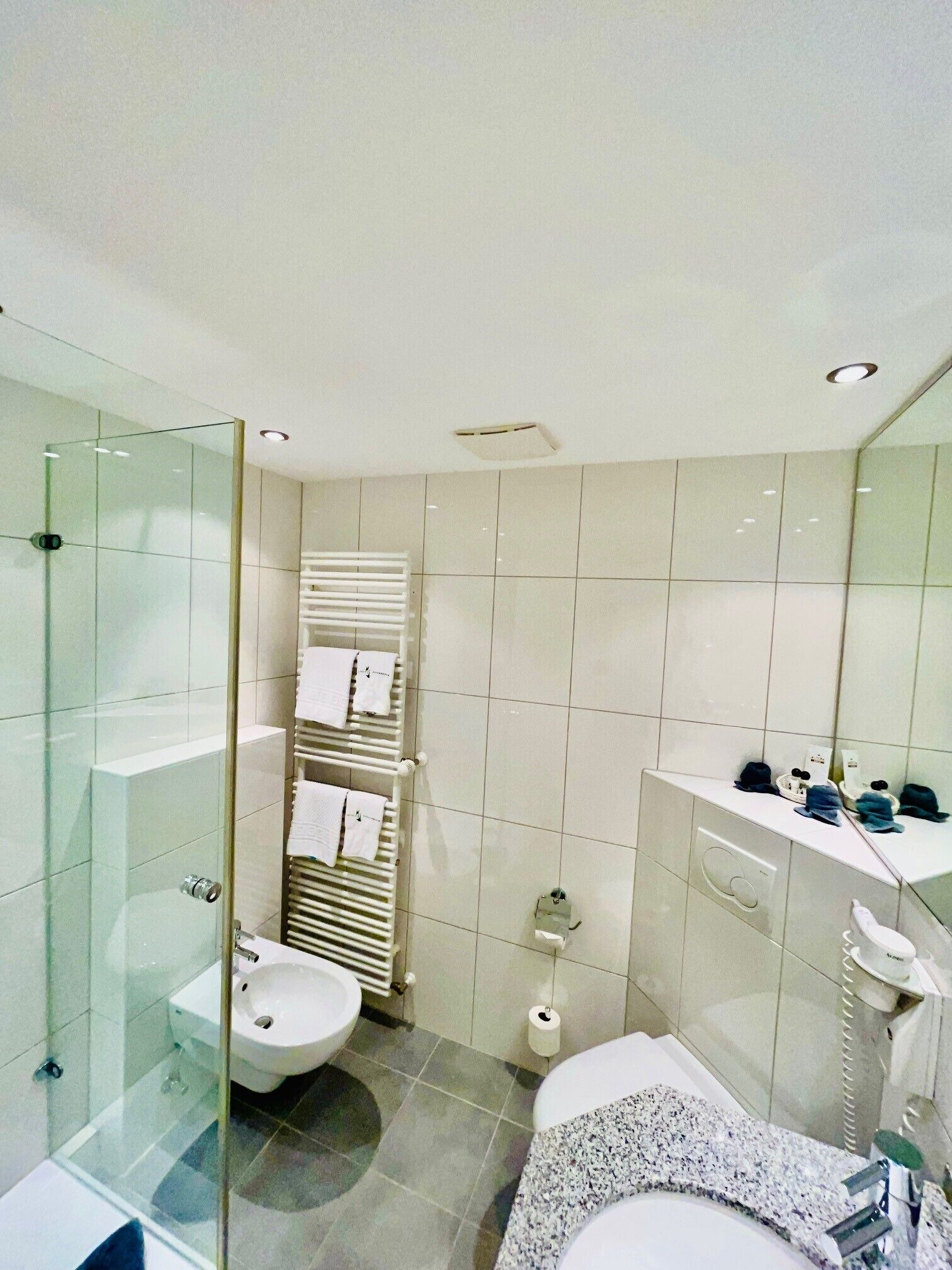 Een moderne badkamer met een douchecabine van glas, een toilet, een bidet en een wastafel.