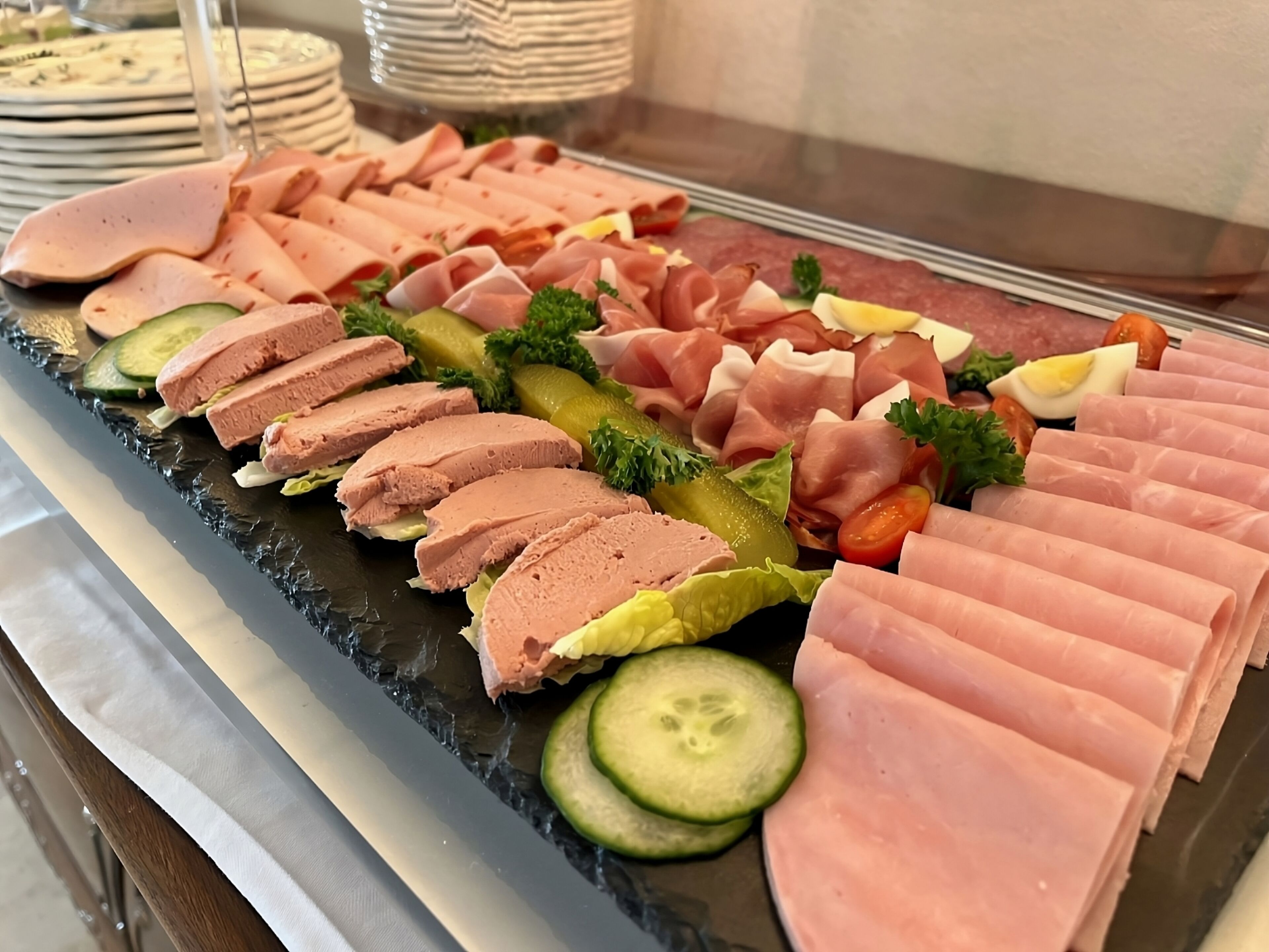 A charcuterie board with various meats, cheeses, and pickles.