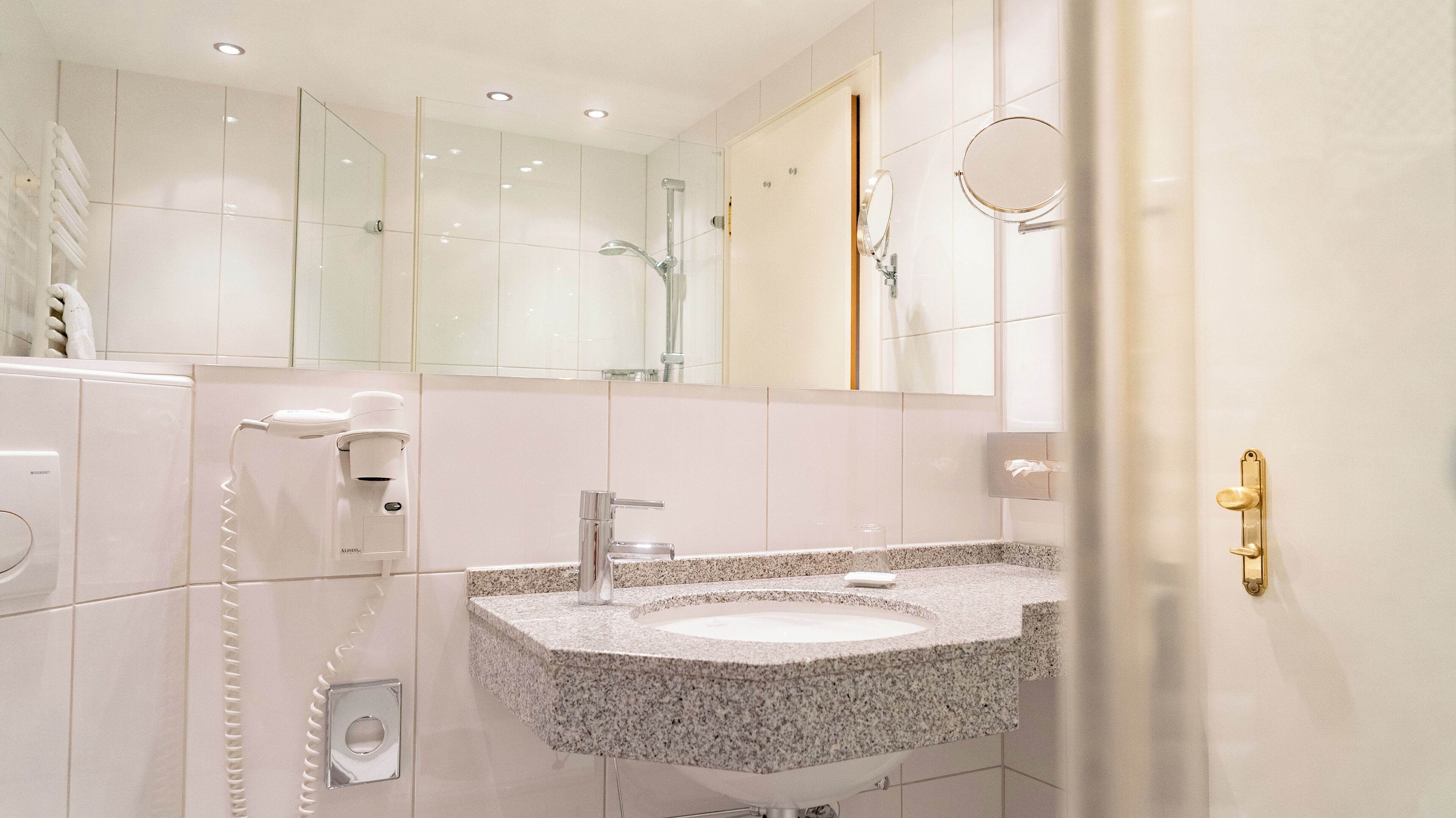 Ein modernes Badezimmer mit Waschbecken aus Granit, einer Handbrause und einem Handtuchspender.