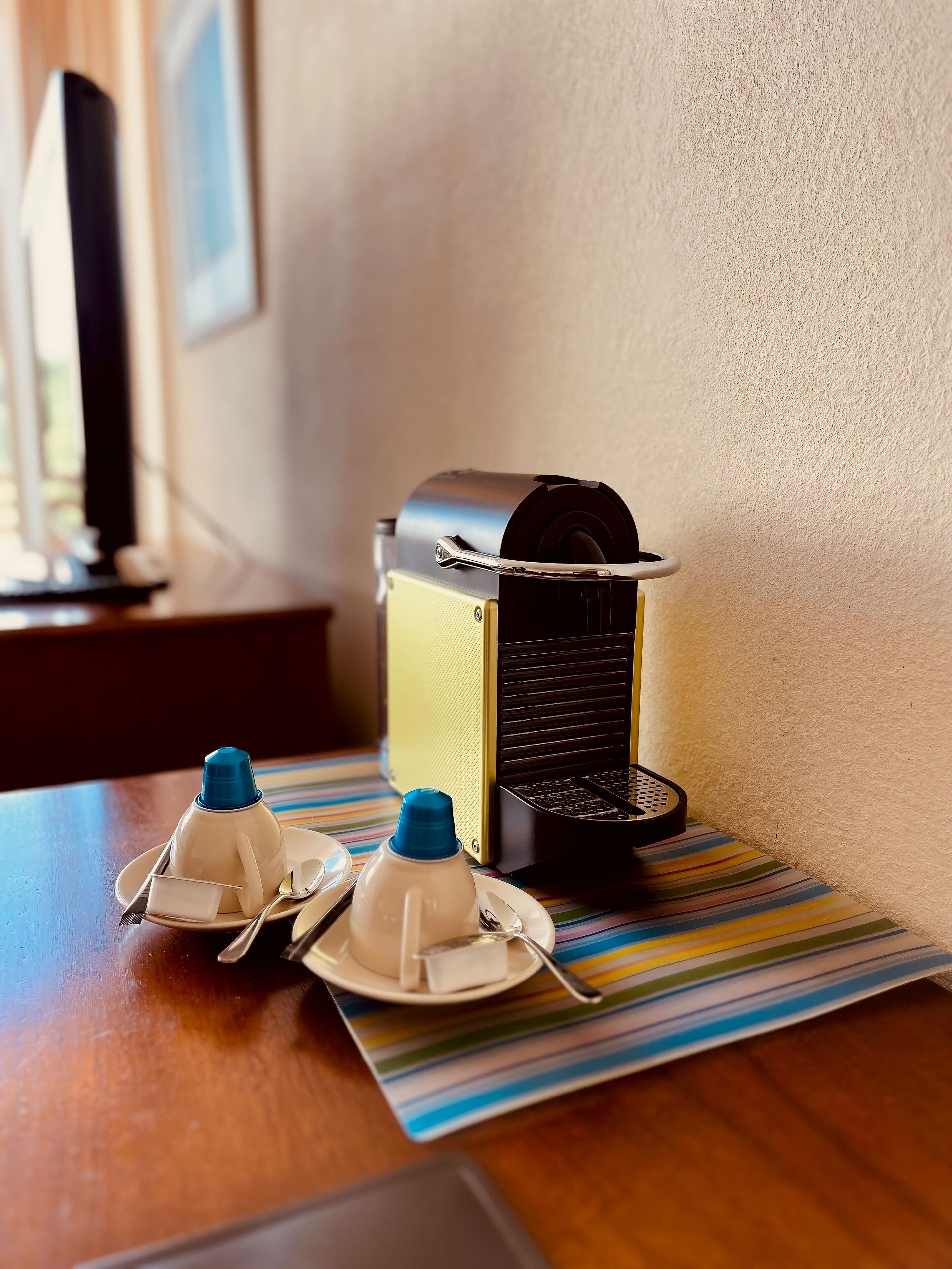 Une table avec une machine à café, deux tasses et une cuillère.