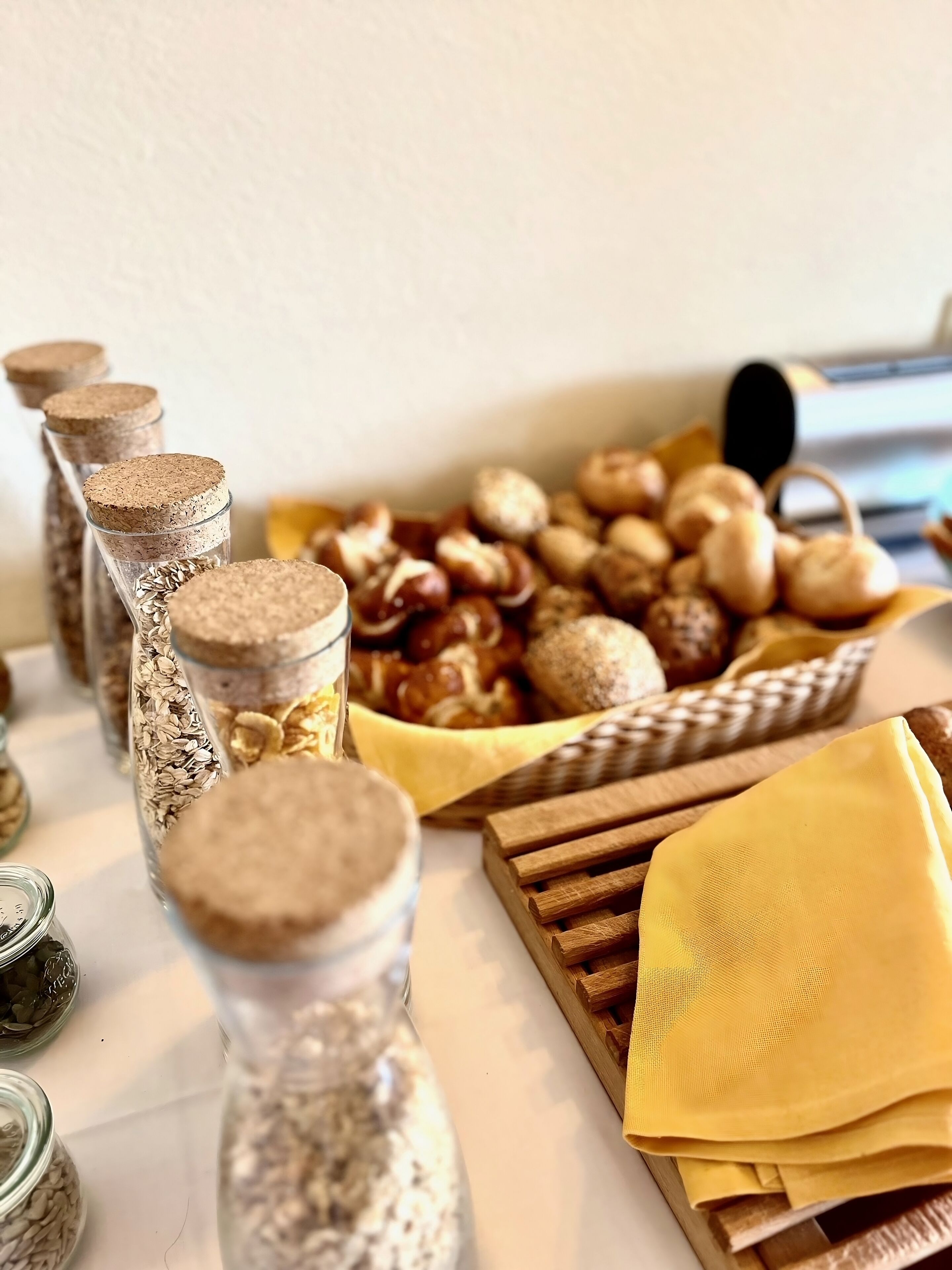 A table with jars of grains, a basket of nuts, and wooden slats.