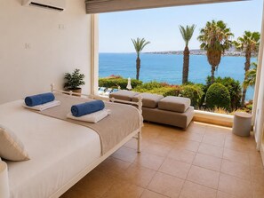 A bedroom with a bed, a sofa, and a view of the sea.