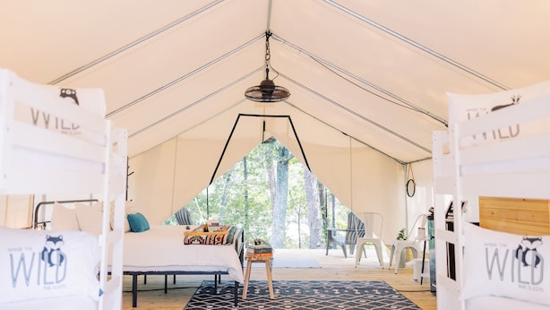 A tented accommodation with a bed, a small table, and a view of trees through the entrance. - Luxury Spacious Glamping, Lake View, Grill, Pool, Pet Friendly, Swim (Delta)