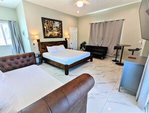 A hotel room with a large bed, a sofa, a desk, and a painting on the wall.