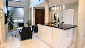 Una cocina moderna con cubierta de encimera negra, armarios blancos y un comedor con mesa y sillas redondas.