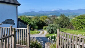 A rural landscape with a stone wall, wooden fence, and a gravel path leading through greenery. - Red Kites Retreat (Eglwysbach)