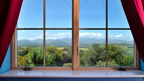 A window with a view of green hills and a clear sky. - Red Kites Retreat (Eglwysbach)