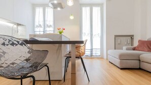 A modern kitchen with a marble countertop, a glass chair, and a wooden dining table. - Design Premium apartment in center Milan-HomeUnity (Milano)