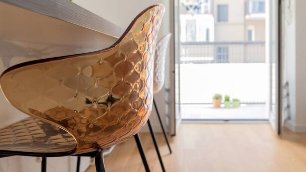 A modern interior with a reflective metallic chair, a wooden table, and a balcony with a view of buildings. - Design Premium apartment in center Milan-HomeUnity (Milano)