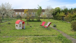 A grassy outdoor area with a small playhouse and two red chairs.