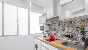 A compact kitchen with a washing machine, a microwave, a sink, and a colorful backsplash. - Las Canteras Beach - Bright Studio - Workfriendly (Las Palmas de Gran Canaria)