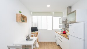 A compact kitchen with a dining area, a washing machine, and a small office setup. - Las Canteras Beach - Bright Studio - Workfriendly (Las Palmas de Gran Canaria)