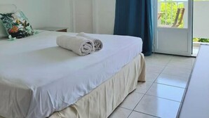 Een hotelkamer met een bed, een raam met gordijnen en uitzicht op groen.