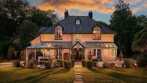 A large, two-story house with a symmetrical facade, a central entrance, and a covered porch with seating.
