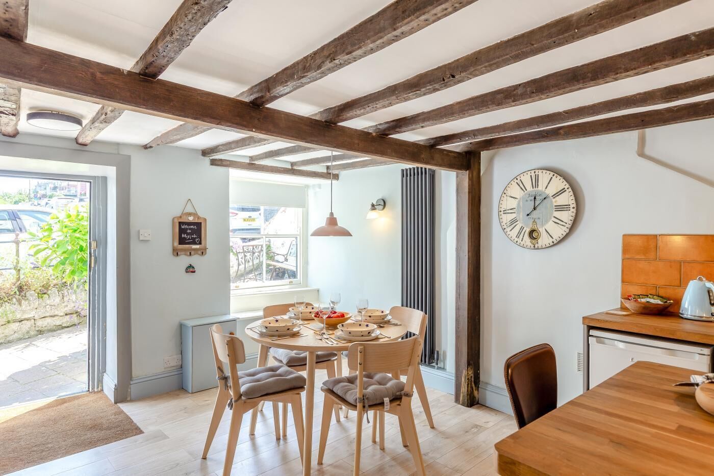 A dining area with a round table, chairs, and a wall clock.