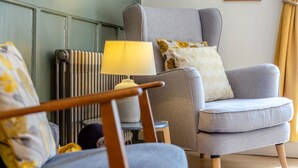A living room with a grey armchair, a small side table, and a lamp.