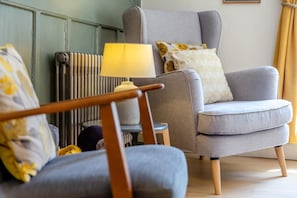A living room with a grey armchair, a small side table, and a lamp.