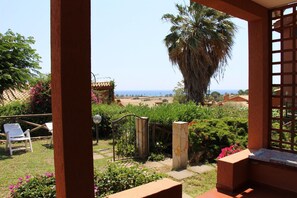 A garden with a view of the sea, a palm tree, and a pergola.
