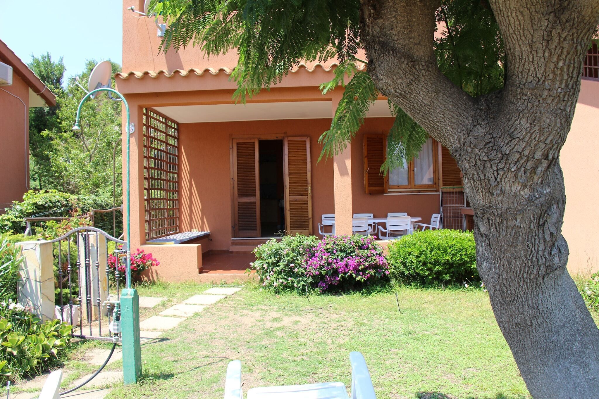 A building with a covered patio, outdoor seating, and a garden area.
