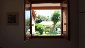 Una habitación con ventana abierta que da a un jardín.