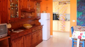 Una cocina con armarios de madera, un refrigerador blanco y una zona de comedor con mantel floreado.