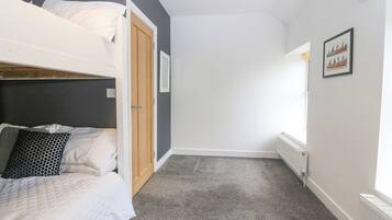 Un dormitorio con literas, una puerta, un radiador y un cuadro en la pared.