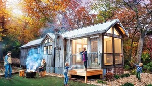 Un chalet rustique avec une façade en bois, une terrasse et un foyer extérieur.