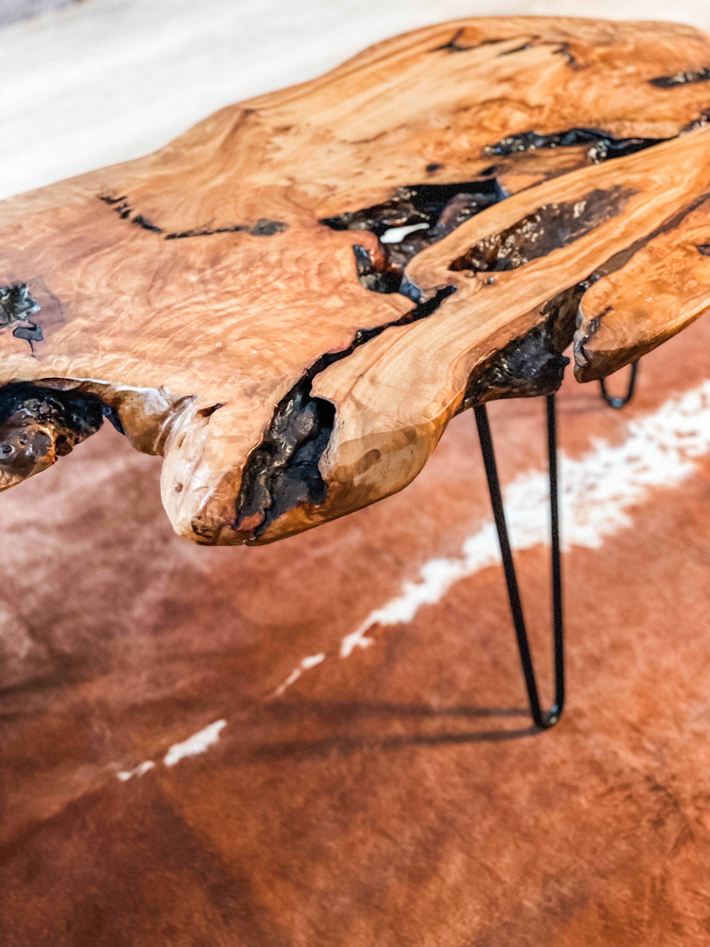 A wooden table with a unique crack design, supported by metal legs.
