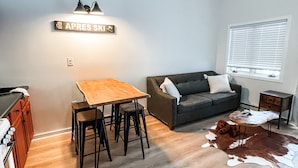 A modern living room with a wooden dining table, a sofa, and a cowhide rug. - Condo with loft near Loon mountain with pool/jacuzzi & free shuttle! (Lincoln)