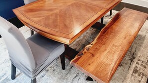 Un espace repas comprenant une grande table en bois, des chaises rembourrées et un banc.