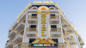 Un immeuble à plusieurs étages sur lequel on peut voir une enseigne bien visible indiquant « GOLDEN HOTEL ».