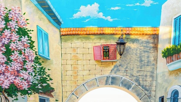 Une terrasse agrémentée de chaises dorées à motifs et d’une table, un mur en pierre et une vue dégagée sur l’extérieur, visible à travers une arche.