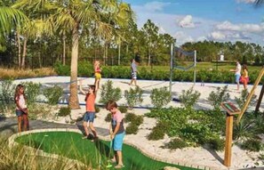 A beach volleyball court surrounded by palm trees and greenery. - Orlando Townhome Resort Private Heated Plunge Pool (Davenport)