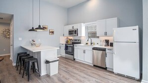 A modern kitchen with white cabinets, stainless steel appliances, and a central island with stools. - Charming 3BR/2BA Gem Close to Downtown/ Riverwalk (San Antonio)