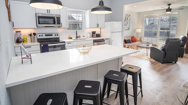 A modern kitchen with white cabinets, a central island with stools, and pendant lighting. - Charming 3BR/2BA Gem Close to Downtown/ Riverwalk (San Antonio)