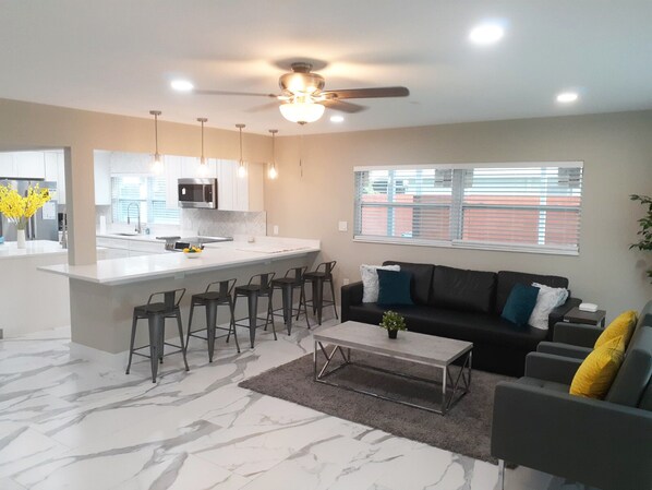 Relax in this stylish living space with a central kitchen island, sofa, and bar stools.