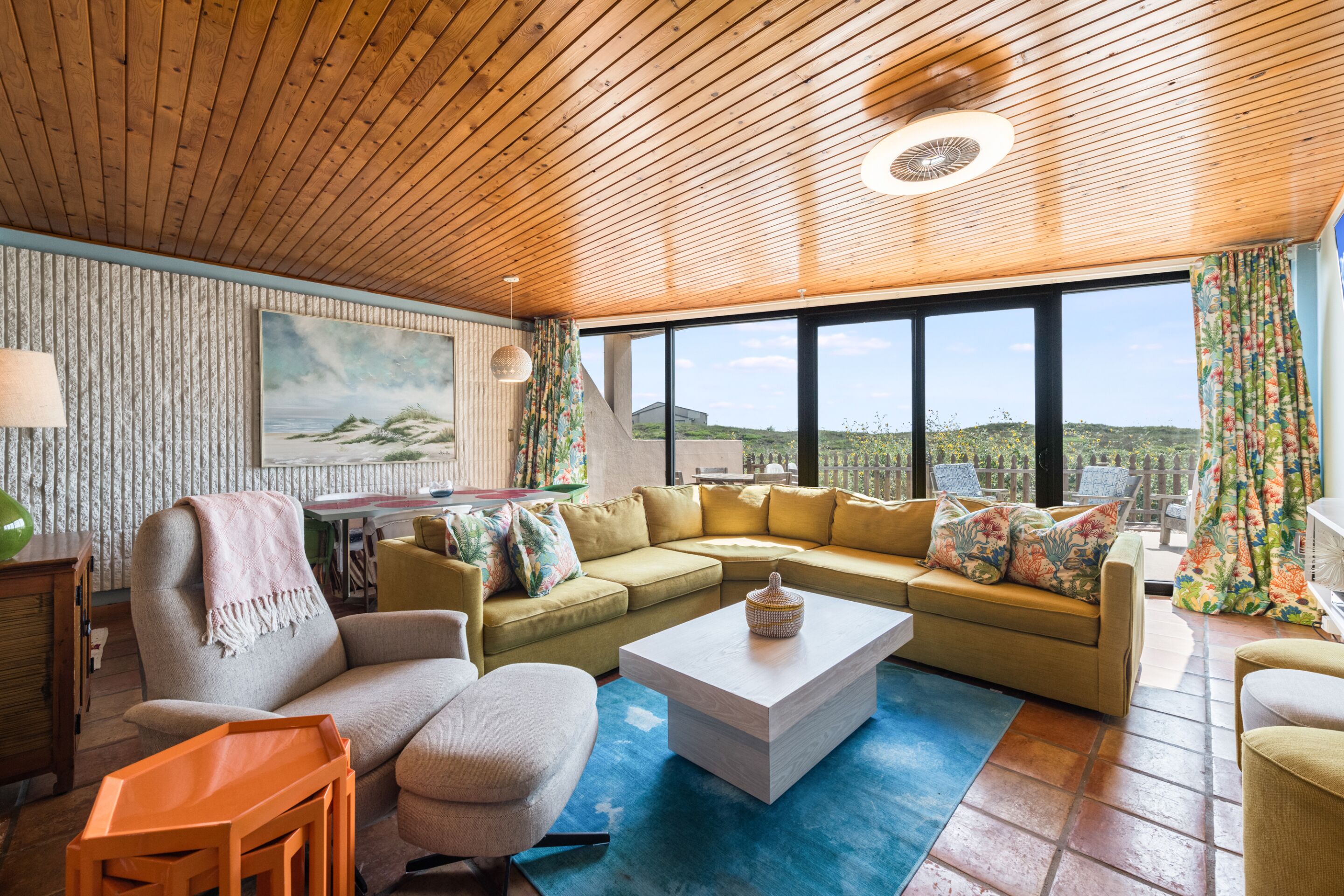 Un salón acogedor con techo de madera, un ventanal con vistas y un sofá seccional.