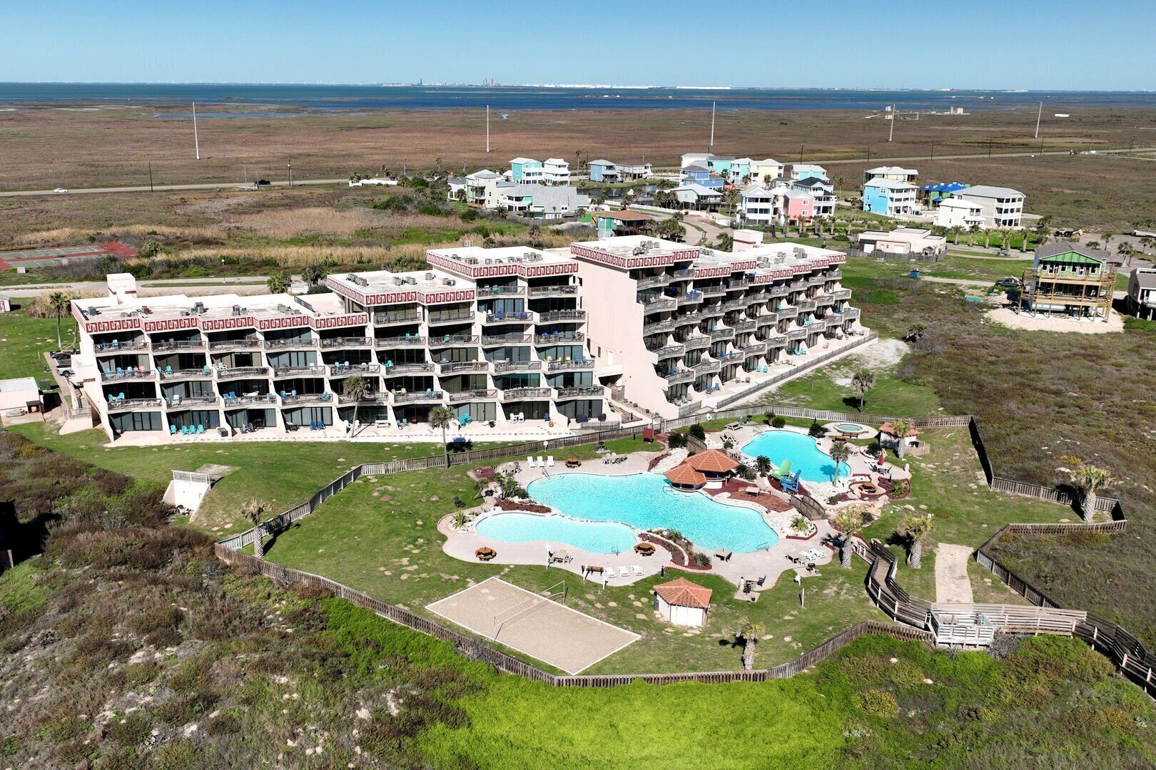 Un gran hotel con múltiples balcones, una piscina central y vista al océano.