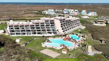 Un gran hotel con múltiples balcones, una piscina central y vista al océano.