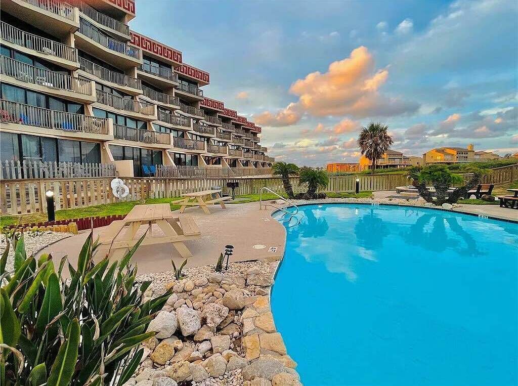 Un hôtel doté d’une grande piscine, de nombreux balcons et d’un jardin bien entretenu.