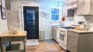 Une cuisine avec un plancher en bois, une cuisinière, des placards et un évier.