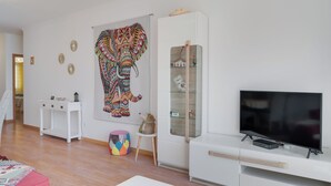 Een moderne woonkamer met een groot, kleurrijk olifant kunstwerk, een glazen displaykast en een flatscreen televisie.